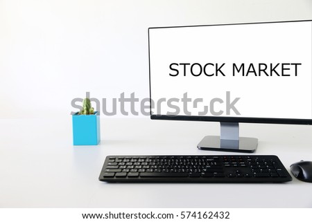 Computer screen on wooden desk with text STOCK MARKET in modern office
