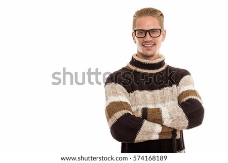 Studio shot of happy young handsome man smiling while wearing eyeglasses with arms crossed