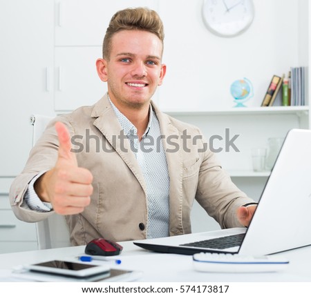 Happy manager with thumbs up gesture at office desk 