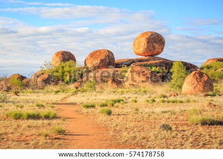 One main boulder and others sit upon a natural rock formation at Karlu Karlu or Devil's Marbles on a fine day. Royalty-Free Stock Photo #574178758