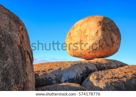 A single boulder sits on a large rock formation at Karlu Karlu or Devil's Marbles. Royalty-Free Stock Photo #574178776
