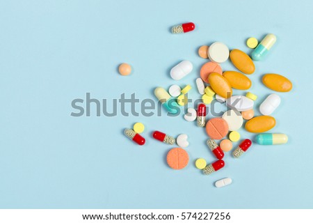 Assorted pharmaceutical medicine pills, tablets and capsules over blue background Royalty-Free Stock Photo #574227256
