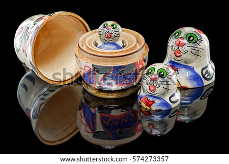 Set of Russian nesting dolls (babushkas or matryoshkas) in shapes of cat family on black mirror