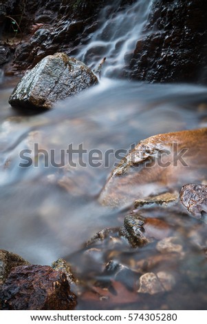 beautiful landscapes : taking photos of satin soft river with rocks flowing in forest in autumn scenery