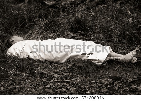 Side view of body of murder victim wrapped in sheet in countryside, black and white picture