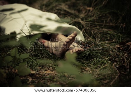 Lower body of abandoned murder victim in dark countryside with bare feet protruding Royalty-Free Stock Photo #574308058