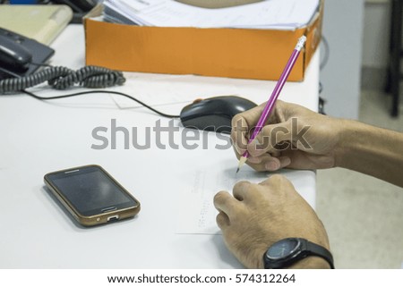 young man writing something on paper in office