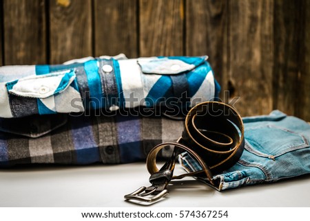 folded men's shirt in the box and the belt with jeans on wooden background ,concept of style and fashion
