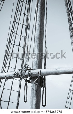 Vintage filtered image of mast of historic timber sailing ship, with rigging and ropes, sky and copy space.