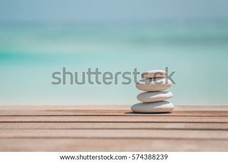 Stones pyramid on pebble tropical beach wooden background.