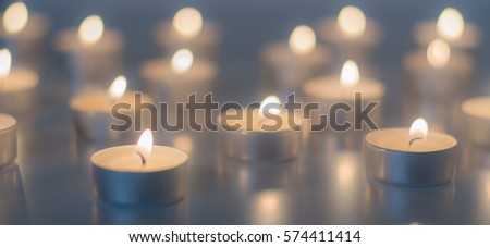 Flame of many candles burning on the background in blue and yellow color