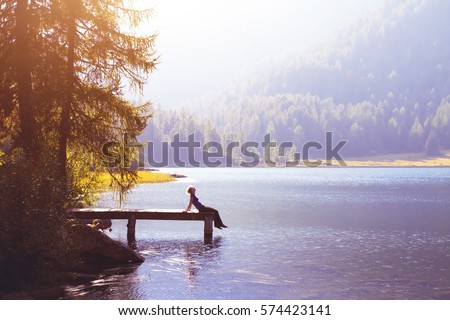 happy woman sitting on the pier and smiling, happiness or inspiration concept, enjoy life Royalty-Free Stock Photo #574423141