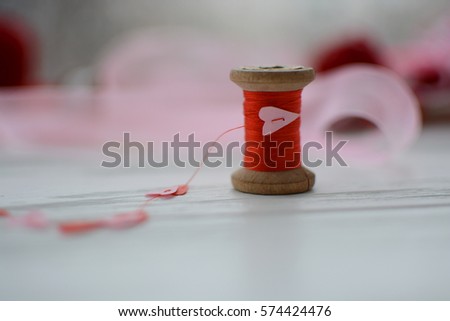 red thread on a spool and hearts