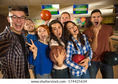 All together. Handsome young cheerful man laughing making a selfie with a group of his happy friends at the bowling club people teens fun leisure activity sports communication weekend friendship