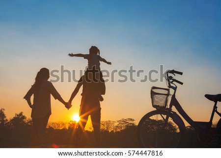 Happy family together, parents with their little child at sunset. Father raising baby up in the airing the sky on a holiday on Chatuchak Park at Bangkok City, Thailand. Concept of friendly family.