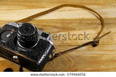 Old retro camera in leather case on the wooden background