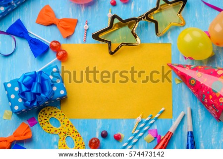 Yellow space in the middle to insert your text. Gift box, golden disco star glasses, cocktail straws, noisemakers, balloons on the blue background. Make your card special.