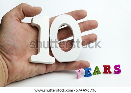 Hand holds a number ten on a white background.