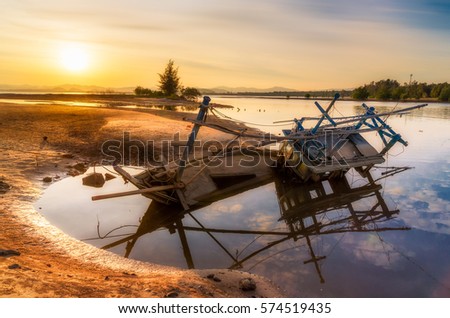Old abandoned fishing boat wrecked stand on a beech with sunset.
