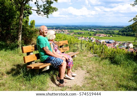 Active senior couple traveling in France. Elderly people visiting Alsace region, enjoying vineyards view from top of Kaysersberg town. Man and woman enjoying french cities, villages and countryside