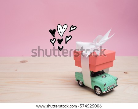 Vintage car carry a  gift box on color background and top wood table for Christmas and The New Year and Valentine's day .Decoration love heart and drawing free hand cartoon cute love.
