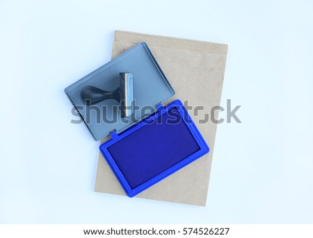 Rubber stamp and Blue Ink cartridges on brown book against white background.
