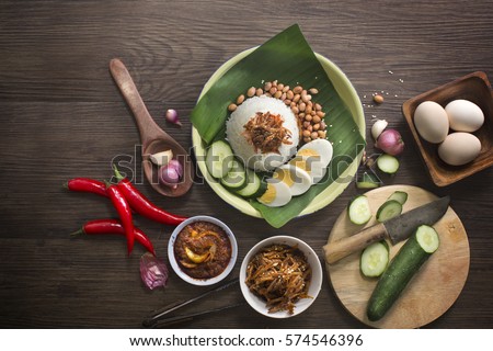 Nasi lemak (Malay fragrant rice dish cooked in coconut milk and pandan leaf) with recipe ingredients on rustic wooden table top. Overhead view image. Royalty-Free Stock Photo #574546396
