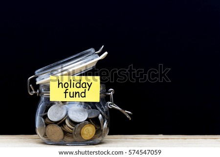 the concept of money, coins in a glass jar on a wooden table and black background