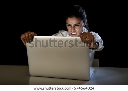 young business woman or student girl working in darkness on laptop computer late at night holding the screen angry in stress and upset in long hour of work concept isolated on black background
