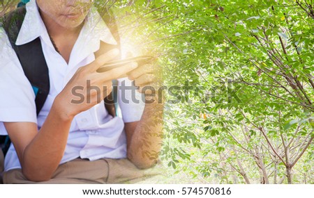 a boy play game on his smart phone seriously with nature background