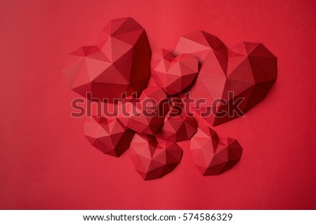 Heap of red polygonal paper heart shapes on red background, top view