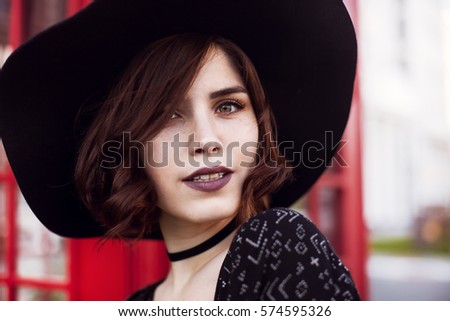 Photo of a young beautiful woman in fashionable hat on the city street.Close up portrait of charming lady. happy girl looking at camera