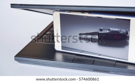 Conceptual image of silver smart phone with text on screen and black laptop on white background