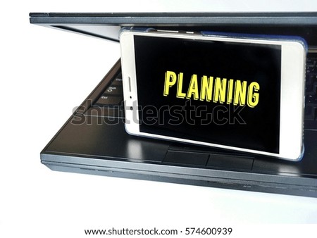 Conceptual image of silver smart phone with text on screen and black laptop on white background