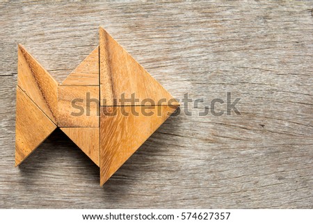Chinese tangram puzzle in fish shape on wooden background