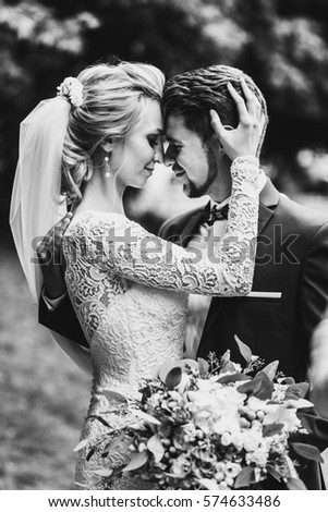 Black and white picture of bride holding groom's head tender while he hugs her back