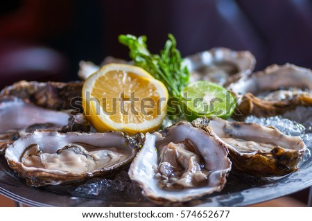 Fresh oyster in dish with lemon and lime  Royalty-Free Stock Photo #574652677