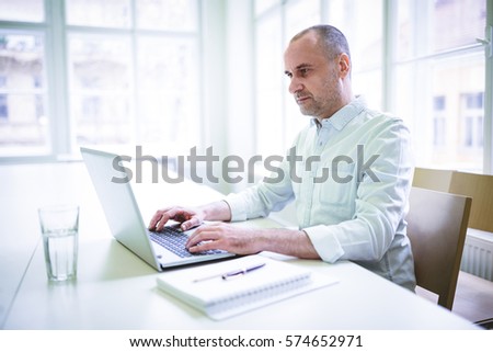 Confident businessman using laptop in creative office