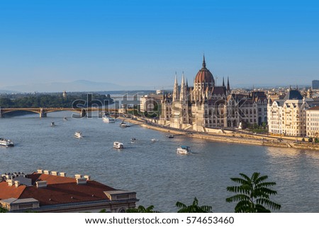 Parliament in Budapest view, with Chain Bridge with lions over river Danube, or Szechenyi Lanchid in Hungarian, on a sunny summer day.  Royalty-Free Stock Photo #574653460