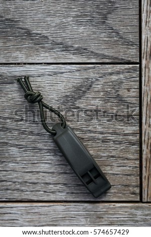 Dark green whistle on natural wood table.