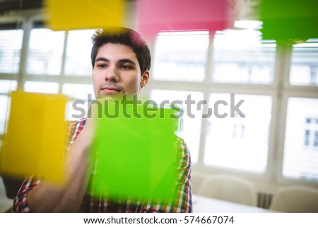 Businessman thinking while looking at sticky notes in creative office