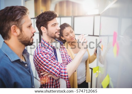 Businessman with young partners looking at whiteboard in creative office Royalty-Free Stock Photo #574712065