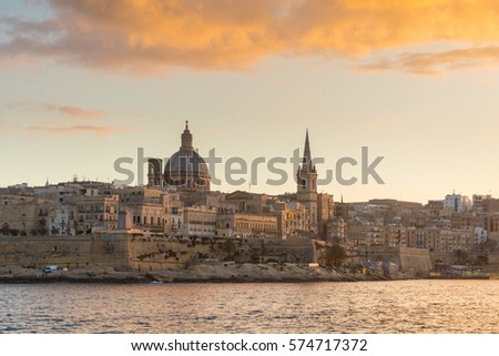 Beautiful spires and cathedral dome of the Valletta skyline under golden clouds at sunset, viewed from Sliema Creek, across Marsamxett Harbour. Valletta, Capital city of Malta