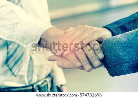Image of businesspeople hands on top of each other as symbol of their partnership,
Hands in color filter.