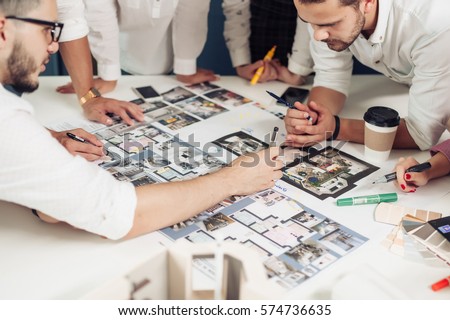 Team of architects working on construction plans Royalty-Free Stock Photo #574736635