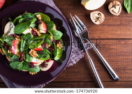 Healthy salad plate with apple, dried cranberry, walnut, spinach and poppy seed dressing on wooden background top view. Food and health. Clean eating.