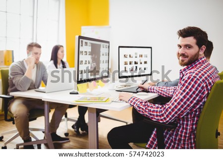 Portrait of happy young male editor working at creative office