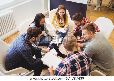 High angle view of business people discussing in meeting room at creative office against projector screen Royalty-Free Stock Photo #574797439