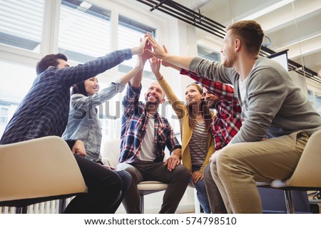 Low angle view of happy creative business people giving high-five in meeting room at creative office Royalty-Free Stock Photo #574798510