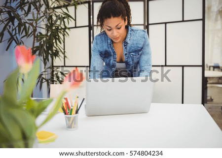 Businesswoman using laptop at desk in creative office